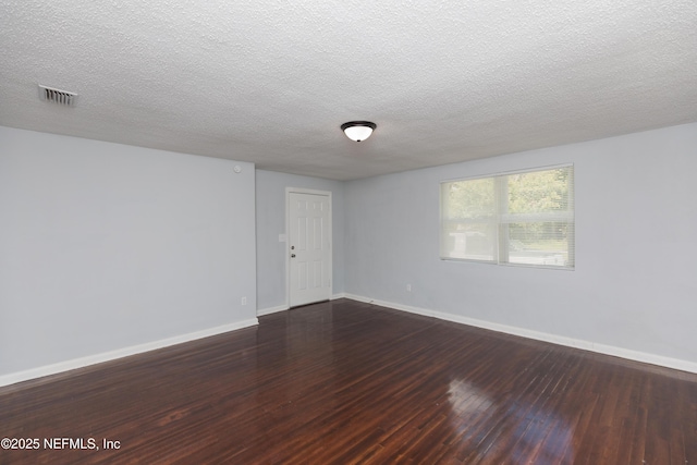 empty room with dark hardwood / wood-style flooring and a textured ceiling