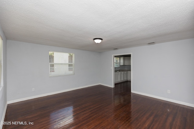 empty room featuring dark wood-type flooring and a textured ceiling