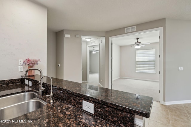 9831 Del Webb Pkwy Unit 3302, Jacksonville, FL 32256 - kitchen featuring light tile patterned floors, dark stone counters, a sink, visible vents, and ceiling fan