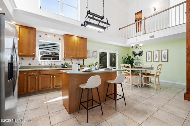 kitchen featuring stainless steel fridge, a kitchen breakfast bar, a center island, light tile patterned flooring, and decorative light fixtures