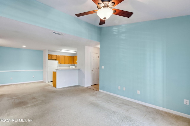 unfurnished living room featuring light carpet and ceiling fan