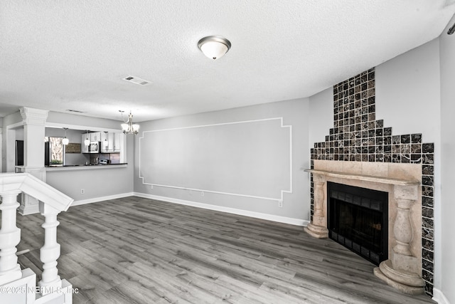 unfurnished living room featuring hardwood / wood-style flooring, a textured ceiling, a fireplace, and a chandelier