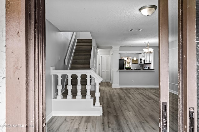 stairs featuring hardwood / wood-style flooring, a notable chandelier, and a textured ceiling