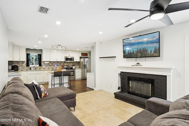 living room with ceiling fan and a fireplace