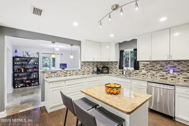 kitchen featuring sink, hanging light fixtures, white cabinets, a kitchen island, and stainless steel dishwasher