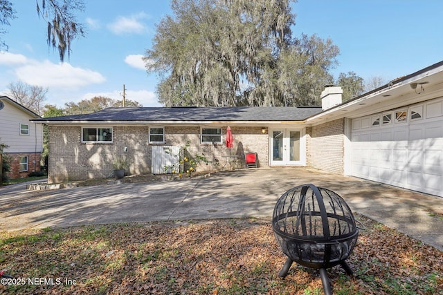 back of house featuring a garage, a fire pit, and french doors