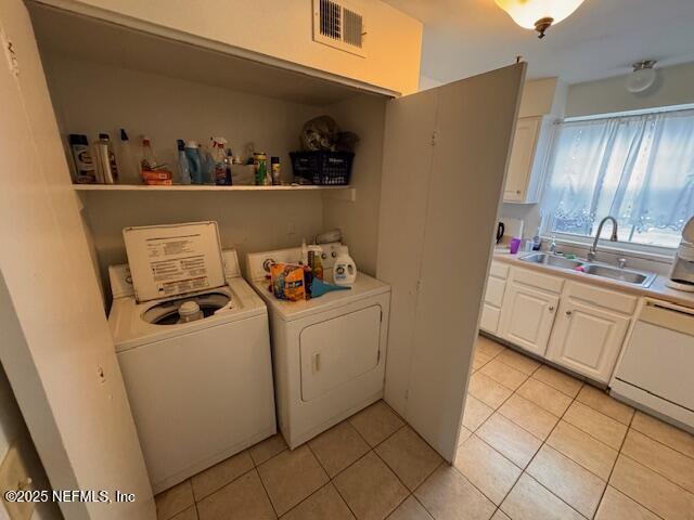 clothes washing area featuring sink, washing machine and dryer, and light tile patterned flooring