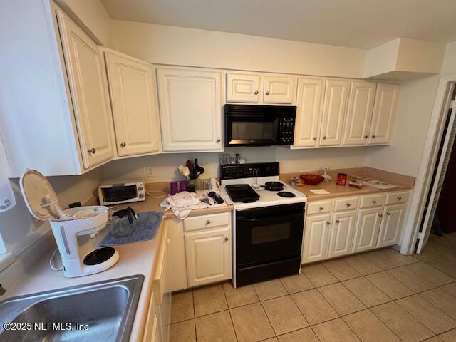 kitchen featuring electric stove, light tile patterned floors, sink, and white cabinets