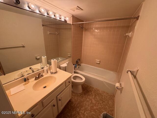 full bathroom featuring vanity, tiled shower / bath, and toilet