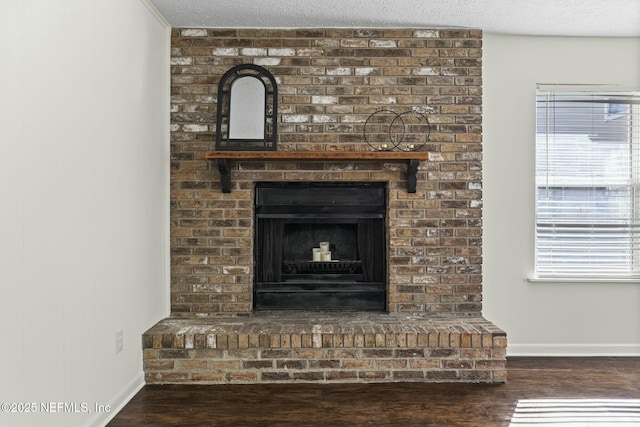 room details with a brick fireplace, a textured ceiling, baseboards, and wood finished floors