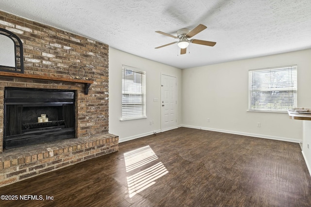 unfurnished living room with a fireplace, ceiling fan, a textured ceiling, wood finished floors, and baseboards