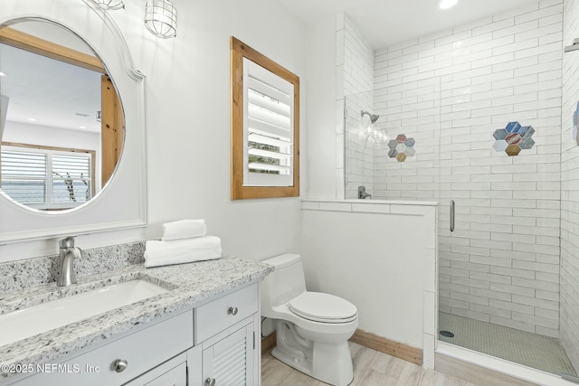 full bath featuring vanity, wood finished floors, a shower stall, and toilet