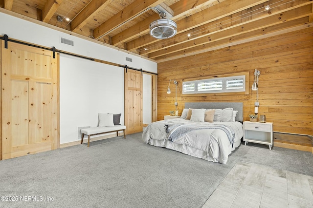 bedroom featuring visible vents, wood walls, carpet flooring, and a barn door