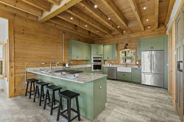 kitchen featuring stainless steel appliances, green cabinetry, wooden walls, and a peninsula