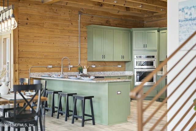 kitchen featuring green cabinets, double oven, a breakfast bar, and wooden walls