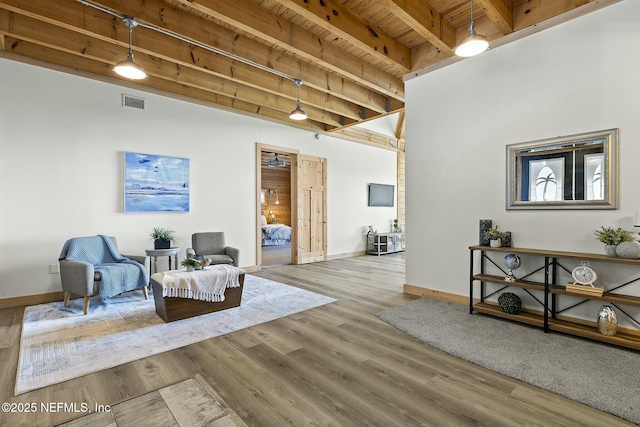 living area featuring visible vents, wood finished floors, wooden ceiling, beamed ceiling, and baseboards