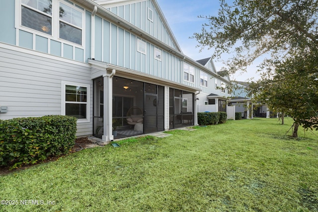 back of house featuring a sunroom and a lawn