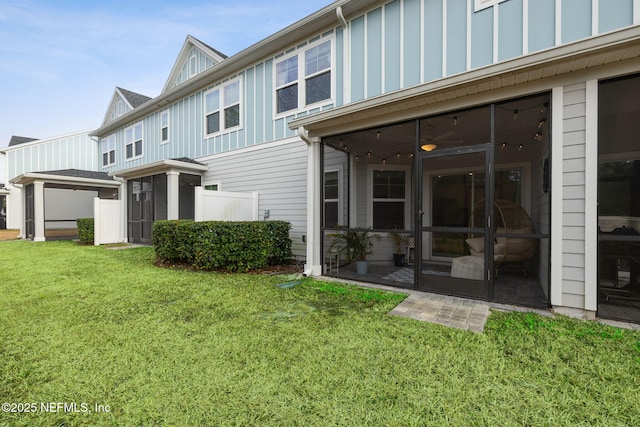 rear view of house with a yard and a sunroom