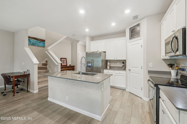 kitchen with stainless steel appliances, white cabinetry, a kitchen island with sink, and sink