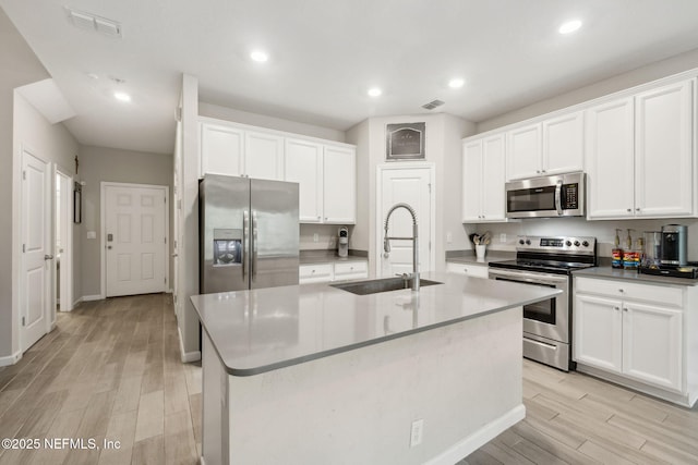 kitchen with sink, light hardwood / wood-style flooring, stainless steel appliances, an island with sink, and white cabinets