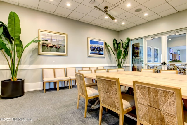 carpeted dining area with a paneled ceiling and french doors