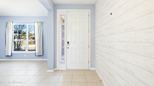 entrance foyer featuring wood walls, baseboards, and light tile patterned floors