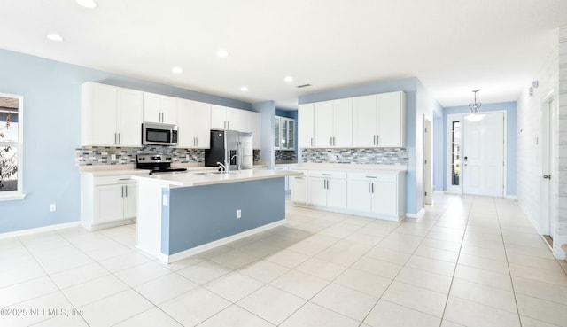 kitchen featuring light countertops, appliances with stainless steel finishes, hanging light fixtures, and white cabinetry