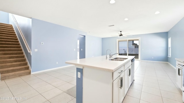 kitchen with light countertops, a sink, a kitchen island with sink, and white cabinets