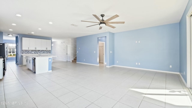 kitchen with light tile patterned floors, tasteful backsplash, open floor plan, light countertops, and white cabinetry