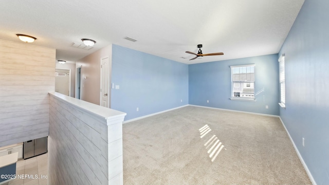 unfurnished room featuring ceiling fan, a textured ceiling, light carpet, and baseboards