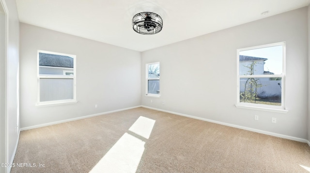 spare room with baseboards and light colored carpet