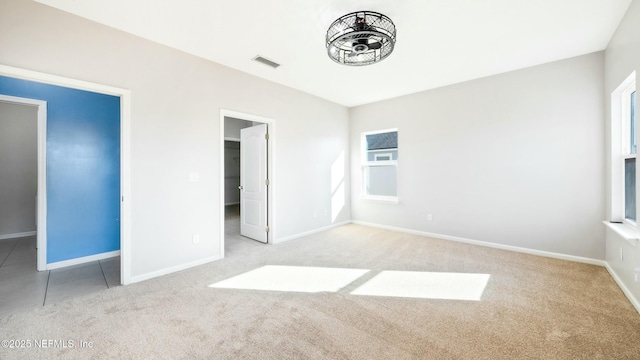 unfurnished bedroom featuring light colored carpet, visible vents, a spacious closet, and baseboards