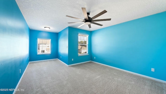 carpeted spare room with a healthy amount of sunlight, baseboards, a ceiling fan, and a textured ceiling