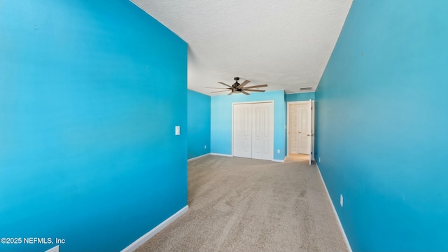 unfurnished room featuring a ceiling fan, light colored carpet, a textured ceiling, and baseboards