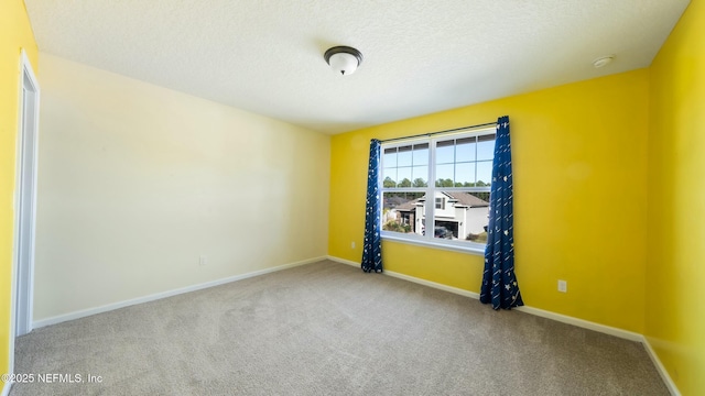 carpeted empty room with baseboards and a textured ceiling