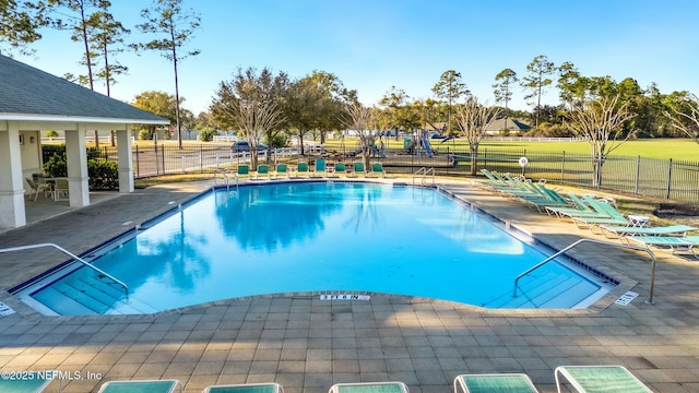 pool with a patio area and fence