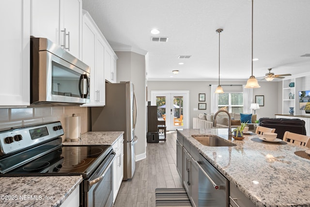 kitchen with appliances with stainless steel finishes, white cabinetry, sink, light stone counters, and french doors