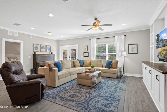 living room with crown molding, french doors, and light wood-type flooring