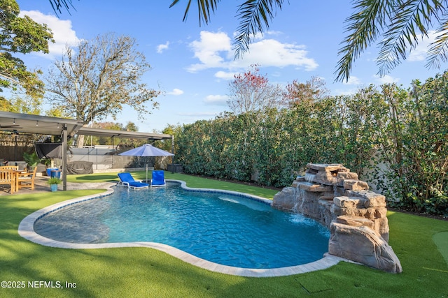 view of swimming pool featuring pool water feature and a lawn