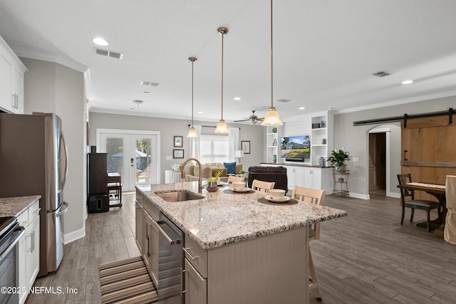 kitchen with decorative light fixtures, an island with sink, sink, a breakfast bar area, and white cabinets