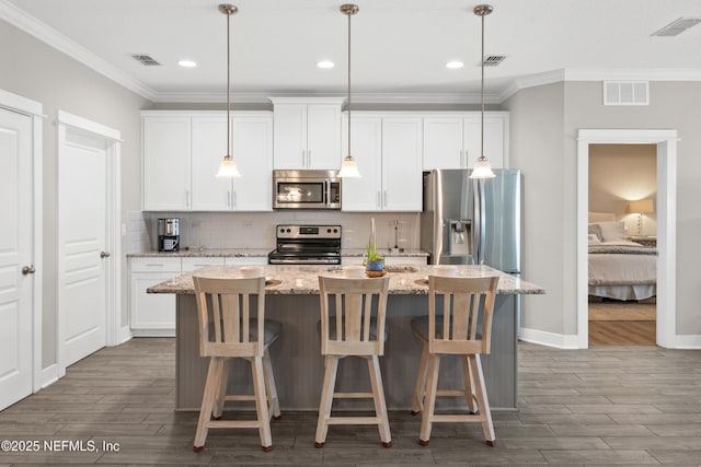 kitchen with an island with sink, appliances with stainless steel finishes, white cabinets, and light stone counters