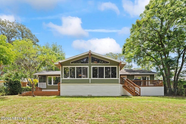 rear view of house featuring a wooden deck, a yard, and a sunroom