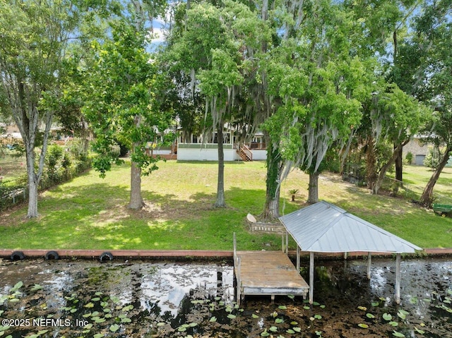 exterior space featuring a dock, a water view, and a lawn