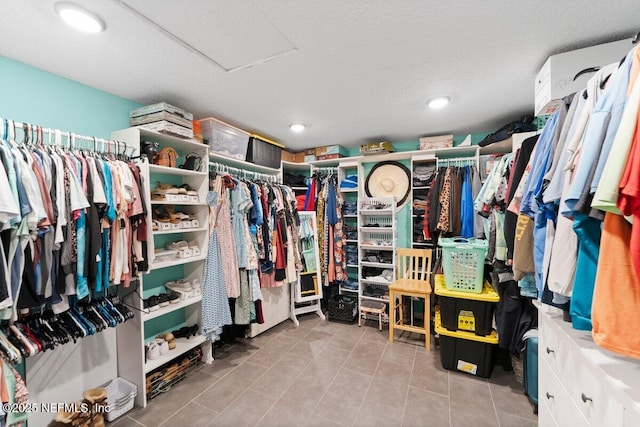 walk in closet with light tile patterned floors