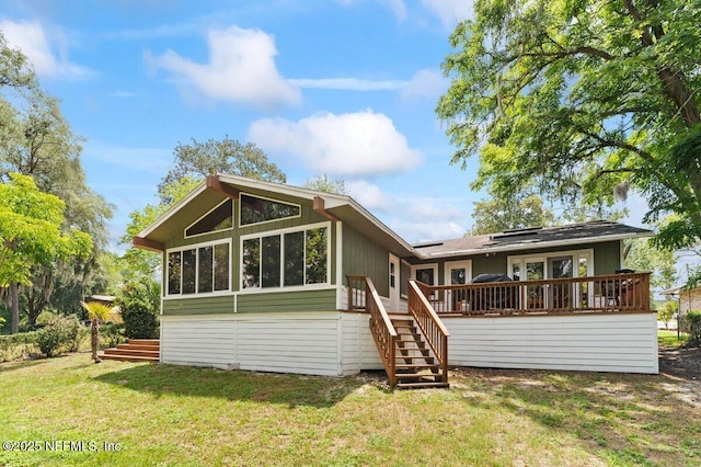 rear view of property featuring a wooden deck, a sunroom, and a yard