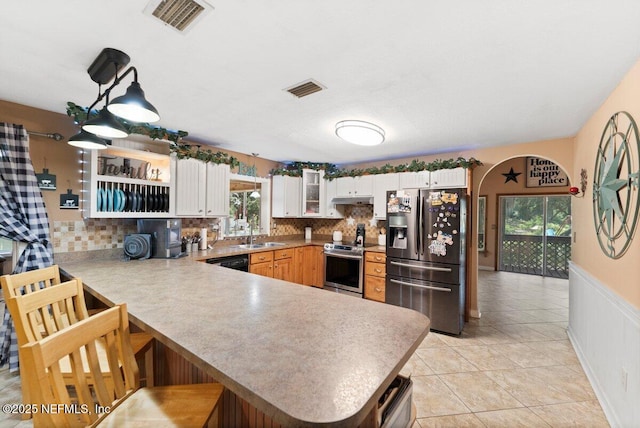 kitchen with pendant lighting, kitchen peninsula, white cabinets, and appliances with stainless steel finishes