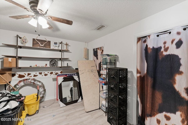 kitchen featuring ceiling fan, light wood-type flooring, white cabinets, and a textured ceiling