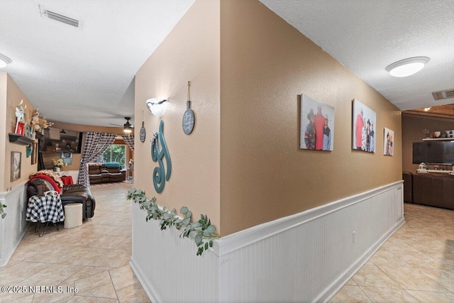 hallway featuring a textured ceiling and light tile patterned floors