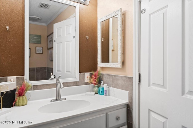 bathroom with ornamental molding, vanity, and tile walls