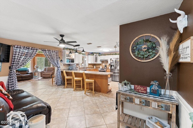 living room featuring ceiling fan, a textured ceiling, and light tile patterned floors